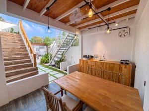 a kitchen and dining room with a wooden table and stairs at Eco Palm Mathiveri - Guest House with Complimentary Shared Kitchen & Laundry in Mathiveri