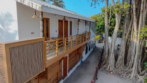a house with a balcony and two palm trees at Eco Palm Mathiveri - Guest House with Complimentary Shared Kitchen & Laundry in Mathiveri