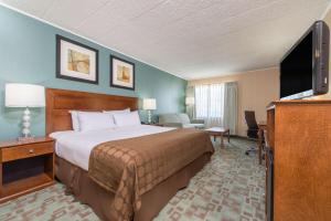 a hotel room with a bed and a flat screen tv at Ramada by Wyndham Vineland Millville Area in Vineland