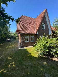 a brick house with a red roof on a yard at Friesenpark 10 in Wurster Nordseeküste