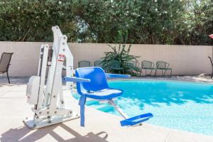a blue chair next to a swimming pool at Super 8 by Wyndham Visalia in Visalia