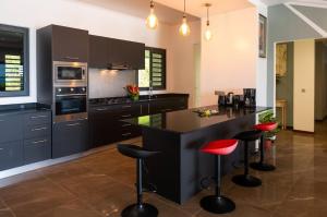 a kitchen with black cabinets and red bar stools at VILLA TUPAOA in Bora Bora