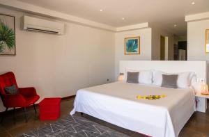 a bedroom with a large white bed and a red chair at VILLA TUPAOA in Bora Bora