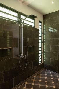 a bathroom with a shower with black tiles at VILLA TUPAOA in Bora Bora