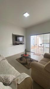 a living room with a couch and a tv at Casa da Clau in Olímpia