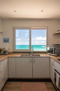 a kitchen with a sink and two windows with the ocean at Matira Lagoon in Bora Bora