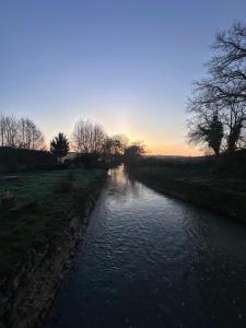 a river with a sunset in the background at Chambre dans un Moulin in Rouy