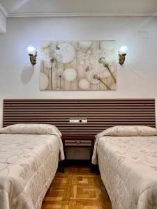 a room with two beds and a painting on the wall at Hotel Castellano I in Salamanca