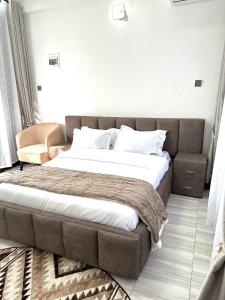a large bed in a bedroom with a couch at Aimarck Homes and Suites in Kampala +4 photos