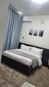 a bedroom with a bed with a blue curtain at Aimarck Homes and Suites in Kampala