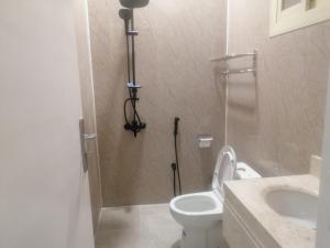 a bathroom with a toilet and a shower and a sink at براون هاوس للشقق المخدومة in Quai
