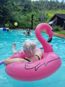 a woman is riding on anlatable flamingo in a pool at Bocaina Sítio da Vovó in Engenheiro Paulo de Frontin