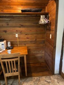 a room with a wooden wall with a table and chair at Cabaña-estudio selvatica in Utila