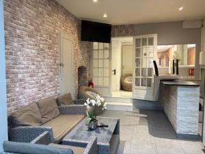 a living room with a couch and a brick wall at Hôtel Le Normandie in Le Mans