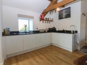 a kitchen with white cabinets and a window at The Studio in Caernarfon