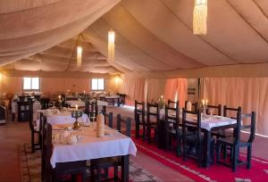 a dining room with tables and chairs in a tent at Merzouga Dream Camp in Merzouga