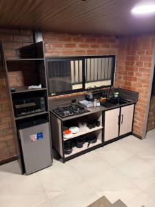 a kitchen with a stove and a brick wall at Relajate en una TinyHouse privada en Baños de Agua Santa con Jacuzzi y vistas increíbles in Baños