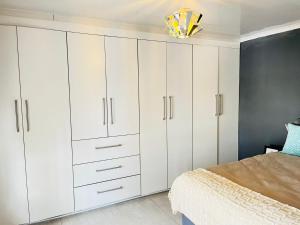 a bedroom with white cabinets and a bed at Legae la rena in Polokwane