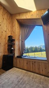 a room with a large window with a view of a field at Nord Hill in Poiana Negrii