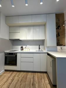a kitchen with white cabinets and a sink at Wine Láà apartamento in Maison Henou