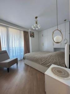 a bedroom with a bed and a chair and a chandelier at Wine Láà apartamento in Maison Henou