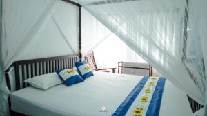 a bedroom with a bed with blue and white pillows at The Duchess Hotel in Matara