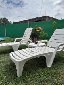 three white lawn chairs sitting in the grass at Las catalinas in General Rodríguez