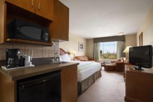 a hotel room with a bed and a television at Super 8 by Wyndham Fort St. John BC in Fort Saint John
