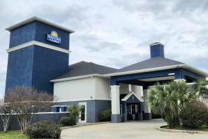 a hotel with a blue building with a sign on it at Days Inn & Suites by Wyndham Thibodaux in Thibodaux