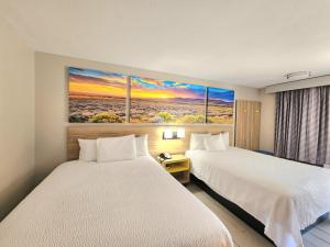 a hotel room with two beds and a painting on the wall at Days Inn by Wyndham McAllen in McAllen +27 photos