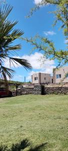 a field with a stone wall and a building at Balcon al dique in Las Chacras