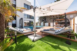 an outdoor patio with lounge chairs and an umbrella at Luxury Villa Elements - Novalja in Novalja