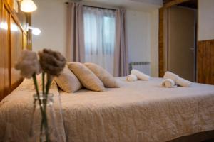 a bed with pillows and a vase with a flower on it at Hostel Buenos Aires in El Calafate