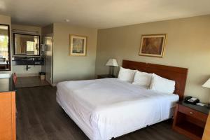 a bedroom with a large white bed and a bathroom at Travelodge by Wyndham Hemet CA in Hemet