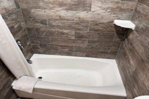 a bath tub in a bathroom with a tiled wall at Travelodge by Wyndham Hemet CA in Hemet +17 photos