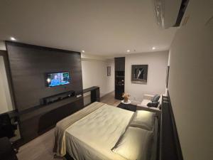 a bedroom with a bed and a flat screen tv at América Executive Apart Hotel Campos - LAMAG in Campos dos Goytacazes