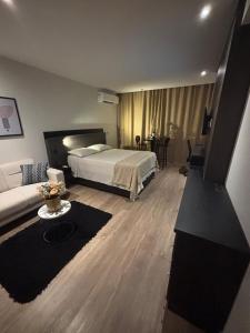 a bedroom with a bed and a living room at América Executive Apart Hotel Campos - LAMAG in Campos dos Goytacazes