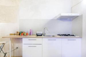een witte keuken met een wastafel en een fornuis bij Dimora nei Sassi in Matera