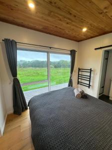 a bedroom with a bed and a large window at The Farm in Whangaruru