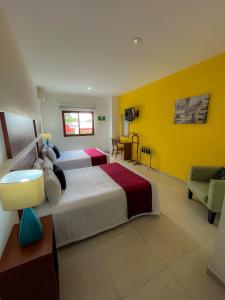 a bedroom with two beds and a yellow wall at Casa de la iaia Hotel in Orizaba +29 photos