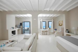 a white living room with a bed and a table at Carpe Diem Santorini in Pyrgos