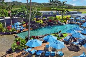 a pool with chairs and umbrellas in a resort at Kiahuna Plantation Resort Kauai by OUTRIGGER in Koloa