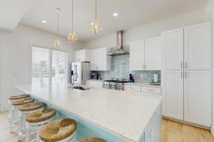 a white kitchen with a large island with bar stools at Tortuga Palms in Rockport