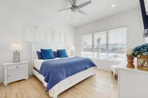 a white bedroom with a bed with blue pillows at Tortuga Palms in Rockport +26 photos