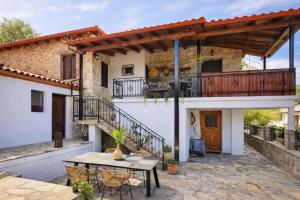 a patio with a table and a balcony at Archontiko Kastellia - Stone Guesthouse with Fireplace and Mountain View in Evangelístria