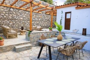 a patio with a table and chairs and a stone wall at Archontiko Kastellia - Stone Guesthouse with Fireplace and Mountain View in Evangelístria