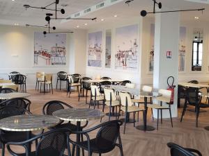 a dining room with tables and chairs and pictures on the walls at Adagio Serris Val d'Europe in Serris