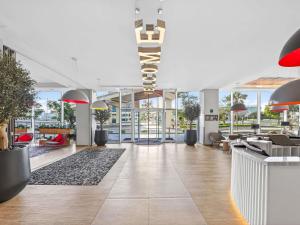 an empty lobby with tables and chairs and plants at ibis Styles Dubai Airport Hotel in Dubai