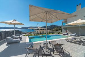 a patio with chairs and umbrellas and a swimming pool at Harmony Apartments in Agioi Apostoli