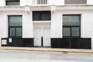 a white house with two white doors and windows at Rota Beach Loft in Rota
